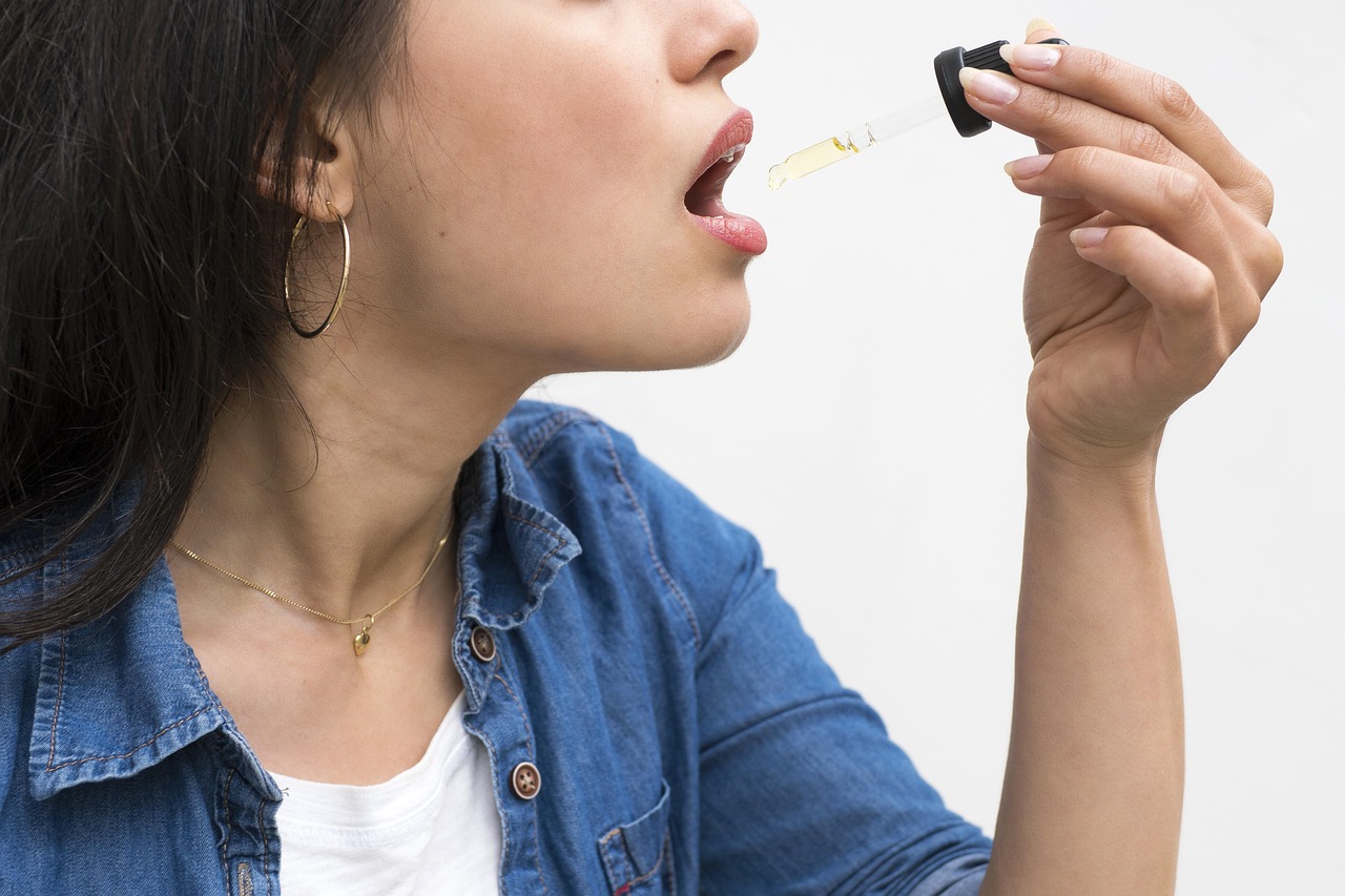 Woman holding a dropper with CBD oil, preparing to take it under her tongue
