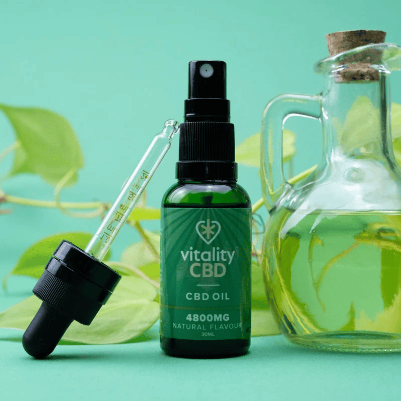 A bottle of Vitality CBD oil with a dropper and a glass carafe